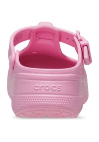 Roze Crocs-klompen gezien vanuit de achterkant, met verstelbare hielband, getextureerde zool en het ingedrukte "crocs" logo.