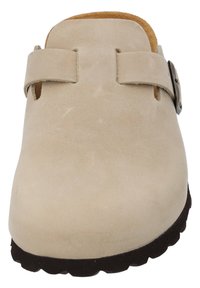 Beige suede clog with a single strap and metal buckle, featuring a textured surface and a rubber sole with a wavy tread pattern.