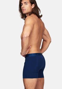 Mörkblå boxershorts med en slät yta och en kontrasterande glansig midja, åtsittande design och längd mitt på låret.