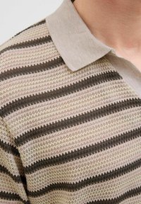 Tricou polo tricotat, cu o bază bej deschis, cu dungi fine alternante închise la culoare, un țesut texturat și un guler moale, pal.