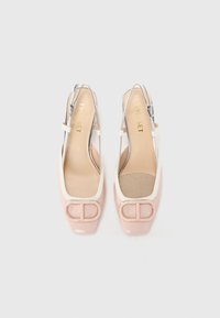 Scarpe slingback in vernice rosa con accenti bianchi, punta quadrata e un logo del designer ben visibile sulla parte frontale. Suola interna in tessuto testurizzato.