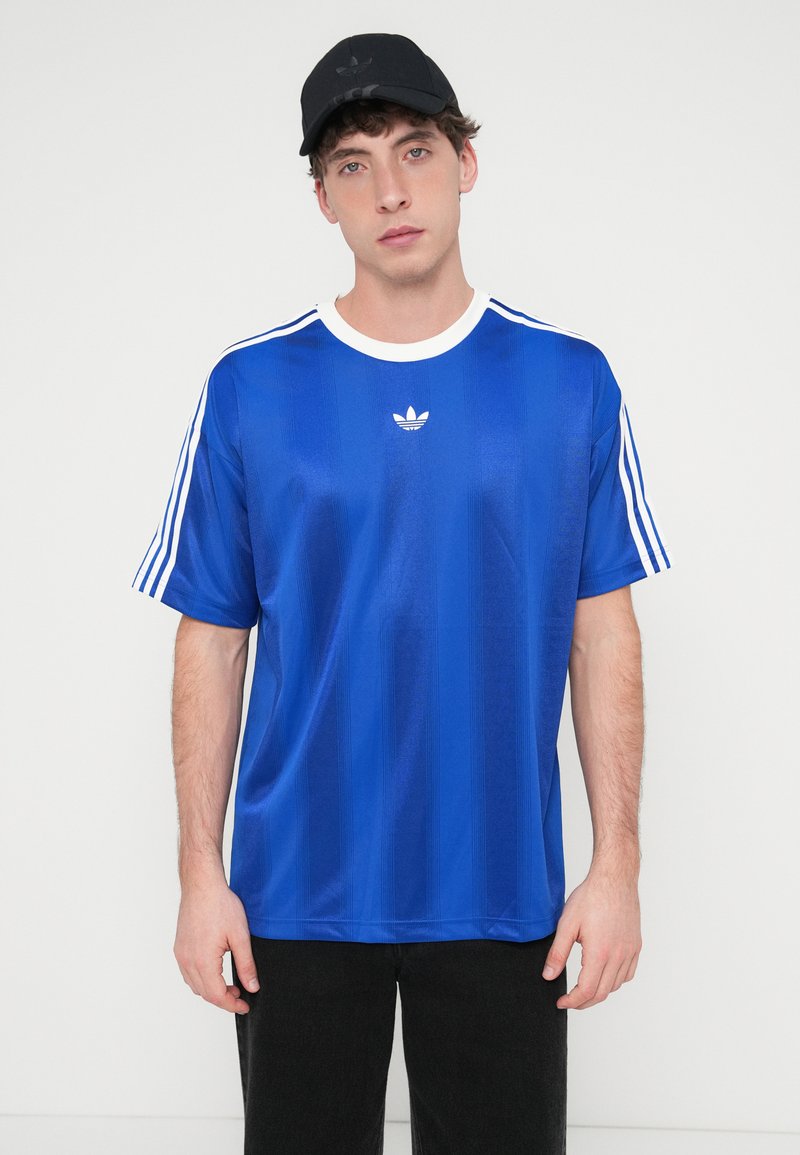 Blaues Sporttrikot mit glatter Textur, weißem Kragen und drei weißen Streifen auf jeder Schulter. Verfügt über ein kleines weißes Logo auf der Brust.