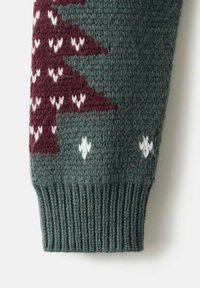 Manche de pull en tricot avec un fond vert foncé et des motifs d'arbres bordeaux et blancs. Texture côtelée au bas.