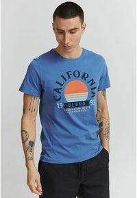 Zila kokvilnas T-krekls ar grafisku dizainu, kurā attēlots saulriets, uzraksts "California" un apaļa apkakle. Īsas piedurknes un brīva piegriezuma.