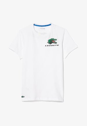Wit T-shirt met korte mouwen en ronde hals met een groen en rood krokodilgrafiek met open mond en "LACOSTE"-tekst op de borst.