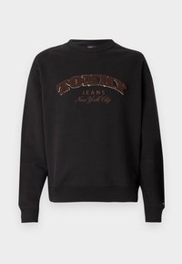 Čierna mikina s okrúhlym výstrihom s výrazným vyšitým logom "TOMMY JEANS New York City" v zlatej a hnedej farbe na prednej strane.