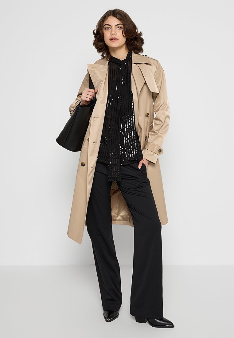 Beige trenchcoat met een gestructureerd ontwerp, zwarte sequinblouse, zwarte broek en een zwarte handtas. Glad textuur, klassieke stijl.