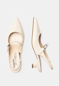 Tacchi in pelle lucida color crema con punta affilata, cinturino slingback e fibbia regolabile. Tacco basso a blocco e finitura interna liscia.