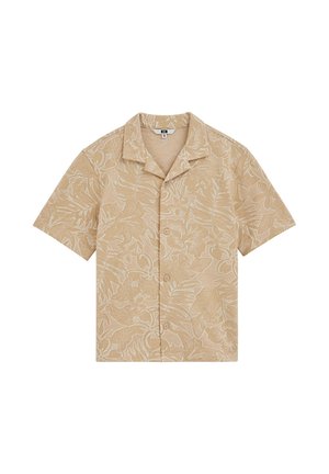 Chemise beige à manches courtes avec motif de feuilles tropicales blanches et col camp, étalée à plat sur fond blanc.