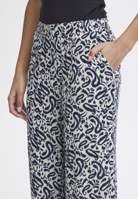 Pantalons légers et à motifs avec une taille élastique. Présentent un design tourbillonnant bleu marine et blanc et des poches latérales. Texture douce.