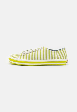 Baskets basses avec des rayures verticales jaunes et blanches, des lacets blancs et une semelle en caoutchouc rayée jaune sur fond blanc.