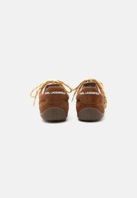 Καφέ σουέντ sneakers με μπεζ κορδόνια, που δείχνουν την πίσω όψη με το "KARL LAGERFELD" γραμμένο με λευκά γράμματα στις πίσω εγκοπές και στις σόλες.