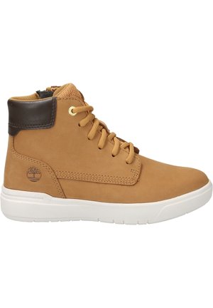 Baskets montantes couleur fauve avec col marron, lacets à l’avant, semelle blanche et logo d’arbre près du talon, présentées sur fond blanc.
