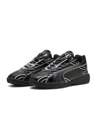 Scarpe da ginnastica nere con finitura lucida, caratterizzate da linee curve bianche e un collare imbottito. La suola è strutturata per garantire aderenza.