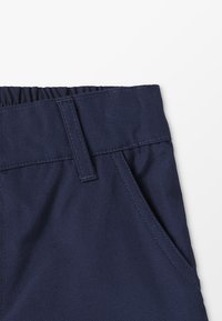 Calças azul-marinho com cintura elástica, bolsos laterais e textura suave. Projeto com corte reto e tecido durável.