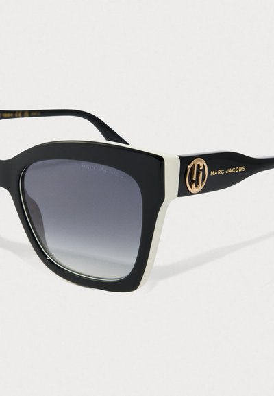 Czarno-białe okulary przeciwsłoneczne w kwadratowej oprawie z gradientowymi szarymi soczewkami, złote logo i branding Marc Jacobs na zauszniku.