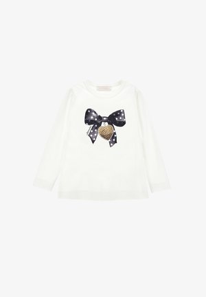Wit shirt met lange mouwen met een zwart-witte polkadot strik en een gouden met studs versierd hart hangertje gedrukt op de voorkant.