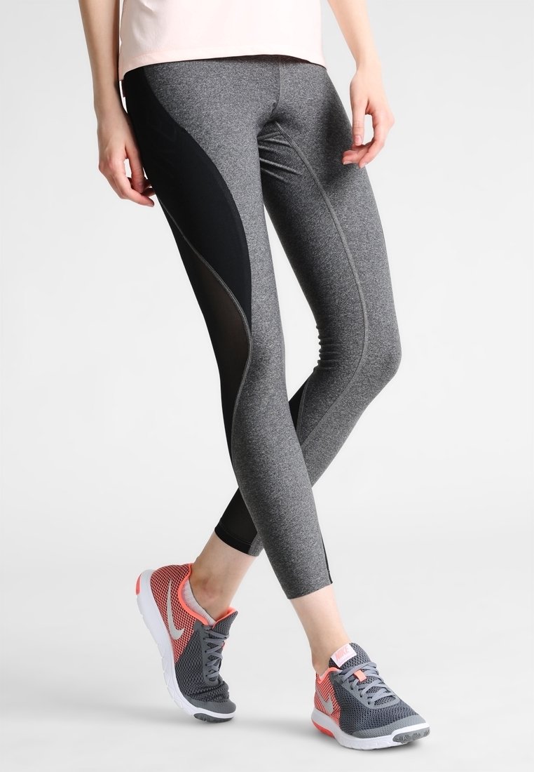 Leggings sportivi grigi a vita alta con pannelli in rete nera e cuciture eleganti, abbinati a scarpe da corsa grigie e rosa.