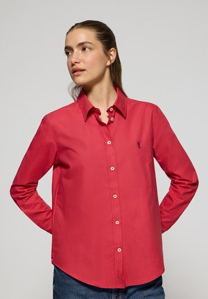 Camicia button-up rossa in cotone con colletto, maniche lunghe e orlo curvo. Presenta un piccolo logo blu sul lato sinistro del petto.