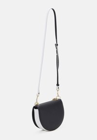 Černo-bílá kožená crossbody taška s zakřiveným tvarem, zlatým kováním a odnímatelným dvoubarevným popruhem. Hladká textura a minimalistický design.