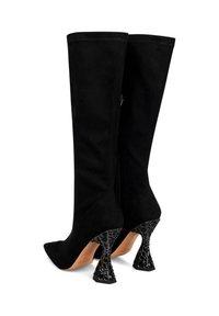Botas altas de ante negro hasta la rodilla con punta afilada y un exclusivo tacón negro escultural que presenta un patrón texturizado. Acabado liso en la parte superior.