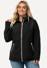 Černá kapucňová bunda s polstrovanou strukturou po stranách, se zipovými kapsami a bílými akcenty na zipu a šňůrkách.