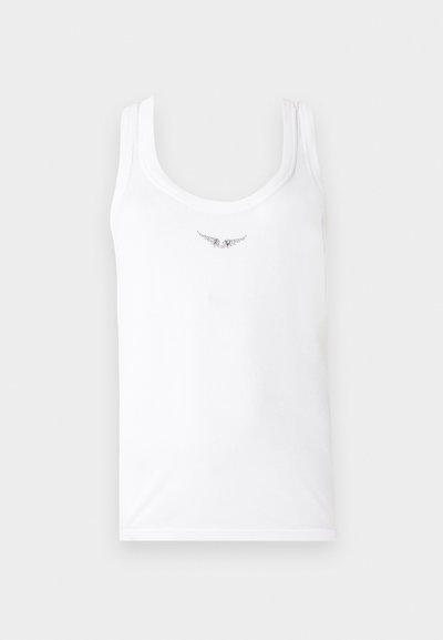 Λευκό αμάνικο μπλουζάκι με μικρό μαύρο αφηρημένο πουά σχέδιο κοντά στη λαιμόκοψη σε απλό φόντο.