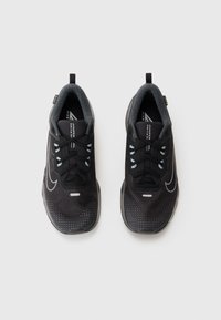 Schwarze Sportschuhe mit einer strukturierten Oberseite, die über ein graues Futter, schwarze Schnürsenkel, reflektierende Akzente und ein Logo auf der Zunge verfügen.