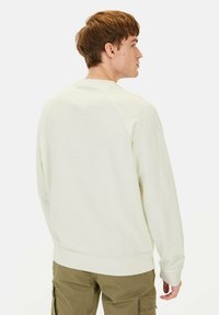 Helles Creme Sweatshirt aus weichem Stoff mit Rundhalsausschnitt und gerippten Bündchen, in lockerer Passform und mit RaglanÄrmeln gestaltet.