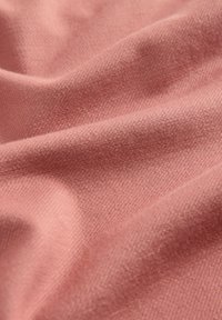 Weicher, strukturierter Stoff in einem sanften Rosa-Ton, der dezente diagonale Webmuster aufweist und geschmeidige, fließende Falten zeigt.