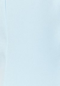 Tissu bleu clair avec une couture verticale, texture lisse et tissage fin, remplissant tout le cadre.