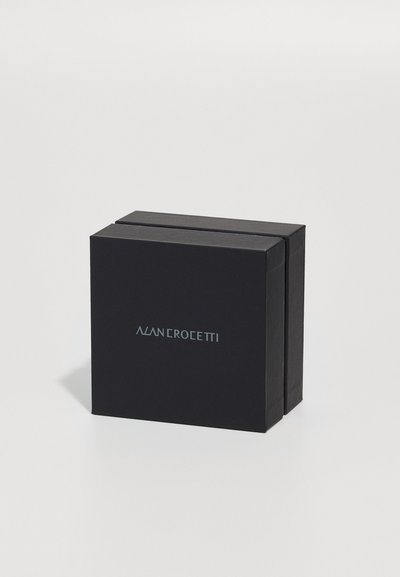 Crni pravokutni kutija s mat završetkom, sivo srebrnim logotipom "ALAN CROCEETTI" na prednjoj strani. Jednostavan, minimalistički dizajn.