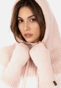 Vaaleanpunainen neulottu huppari ribbaustiedoilla ja sormettomilla hanskoilla. Pehmeä rakenne, jossa on kiristysnauha ja pieni logo-tagi.