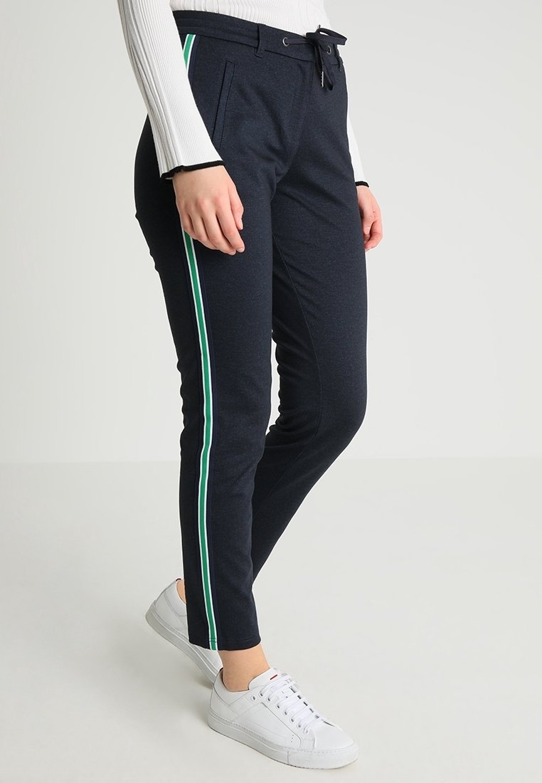 Pantalon de sport bleu marine avec une taille à cordon de serrage et des rayures vertes sur les côtés, fabriqué dans un tissu doux et texturé.