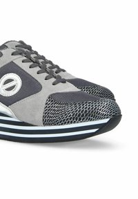 Grijze en marineblauwe sneaker van mesh en suède materiaal, met een gestructureerde neus, witte en zwarte strepen op de zool en opvallend logo-detail.