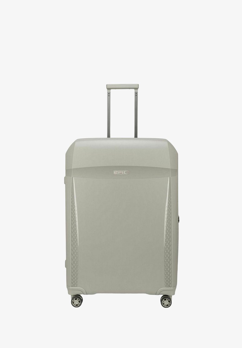 Maleta rígida en gris claro con un acabado texturizado, que cuenta con un mango retráctil y cuatro ruedas para facilitar la movilidad.