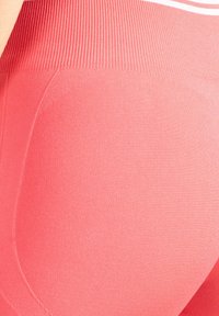 Leggings rosas con una cintura alta acanalada, textura suave y costuras curvas. Presentan un diseño ajustado para mayor comodidad durante el movimiento.