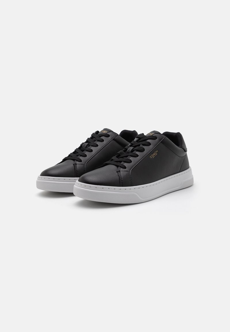 Schwarze Ledersneaker mit einer weißen Gummisohle. Glatte Textur, runde Zehenpartie, Schnürung vorne und dezente goldene Markierung an der Seite.