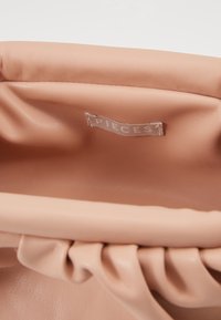Soft pink faux leather bag with a textured interior, featuring subtle pleats and a fabric label reading "PIECES." Simple, unstructured design.