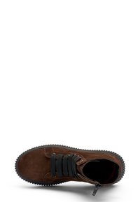 Zapato de ante marrón de caña alta con cordones negros, suela de goma y detalles de cremallera. Textura suave con bordes redondeados y una suela gruesa.