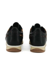 Scarpe sportive nere con esterno in pelle liscia, dettagli arancioni e suola intermedia bianca. Presentano un tacco rotondo e una suola testurizzata.