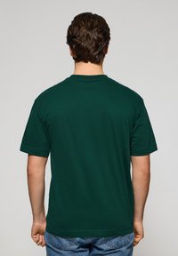Grön kortärmad T-shirt i bomull, med rund halsringning och en enkel design utan synliga mönster eller detaljer.