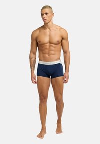 Marineblauwe boxershorts met een zachte elastische witte tailleband. De stof lijkt glad en aansluitend, waardoor de vorm van het lichaam wordt benadrukt. Geen zichtbare patronen.