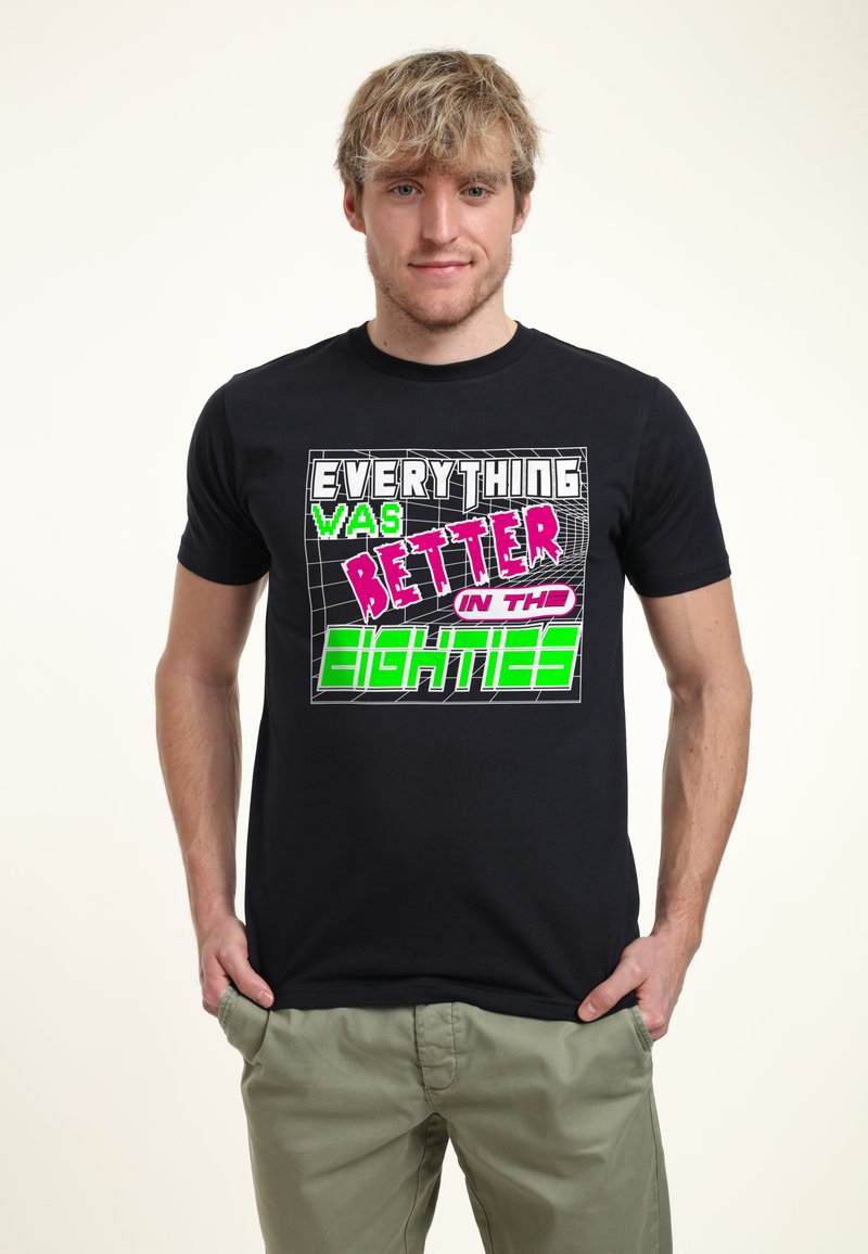 Camiseta de algodón negra con texto impreso colorido que dice "TODO era MEJOR en los OCHENTA" en fuentes negritas y de estilo retro.