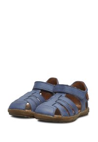 Kožené sandály v modré barvě s výřezy, pásky okolo kotníku a hnědou texturovanou podrážkou. Jsou vidět detaily prošití a mírná podpora klenby.