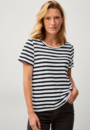 Black and white striped t-shirt made of soft fabric, featuring a crew neckline and short sleeves, worn with dark trousers.