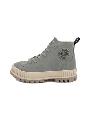 Basket montante grise avec semelle épaisse beige, fermeture à lacets sur le devant et patch rond Palladium sur le côté, avec une languette au talon.