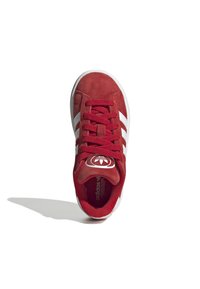 Sneaker rossa in suede con design a tre strisce bianche, logo rotondo sulla linguetta e lacci testurizzati. Suola in gomma con una leggera scolpitura.