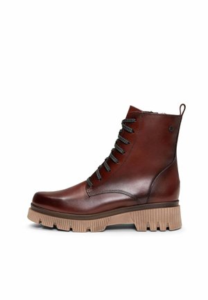 Bota de cuero marrón oscuro con cordones hasta el tobillo, suela gruesa de goma color tostado y lengüeta en el talón, mostrada de perfil sobre un fondo blanco.