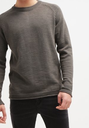 Pull en laine gris foncé avec un col rond, des poignets et un ourlet côtelés, et des manches raglan. La texture est lisse avec de légères variations.